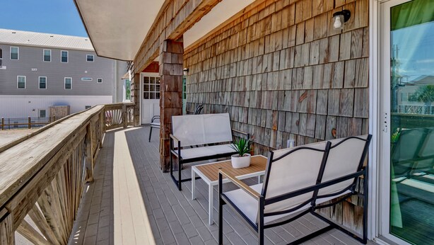 A wooden deck with outdoor furniture, including a table and chairs, and a potted plant. - Family Oasis 1 block from the beach near Boardwalk (Carolina Beach)