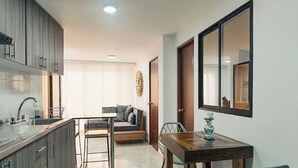 A compact kitchen with dark cabinets, a sink, and a dining area with a table and chairs. - Hermoso y Cómodo Apartamento en El Poblado!!! (Medellín)