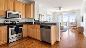 Una cocina con armarios de madera, electrodomésticos de acero inoxidable y suelo de madera.