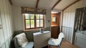 Una habitación acogedora con techo de madera, un escritorio con silla y ventana con vistas a zonas verdes.