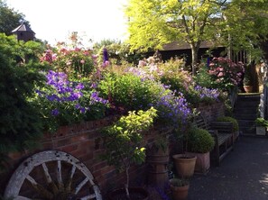 A garden with a brick wall, a wooden bench, and a large wheel.