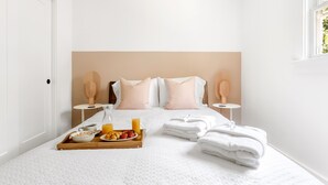 Una cama bien tendida con almohadas, una bandeja con alimentos para el desayuno y toallas.