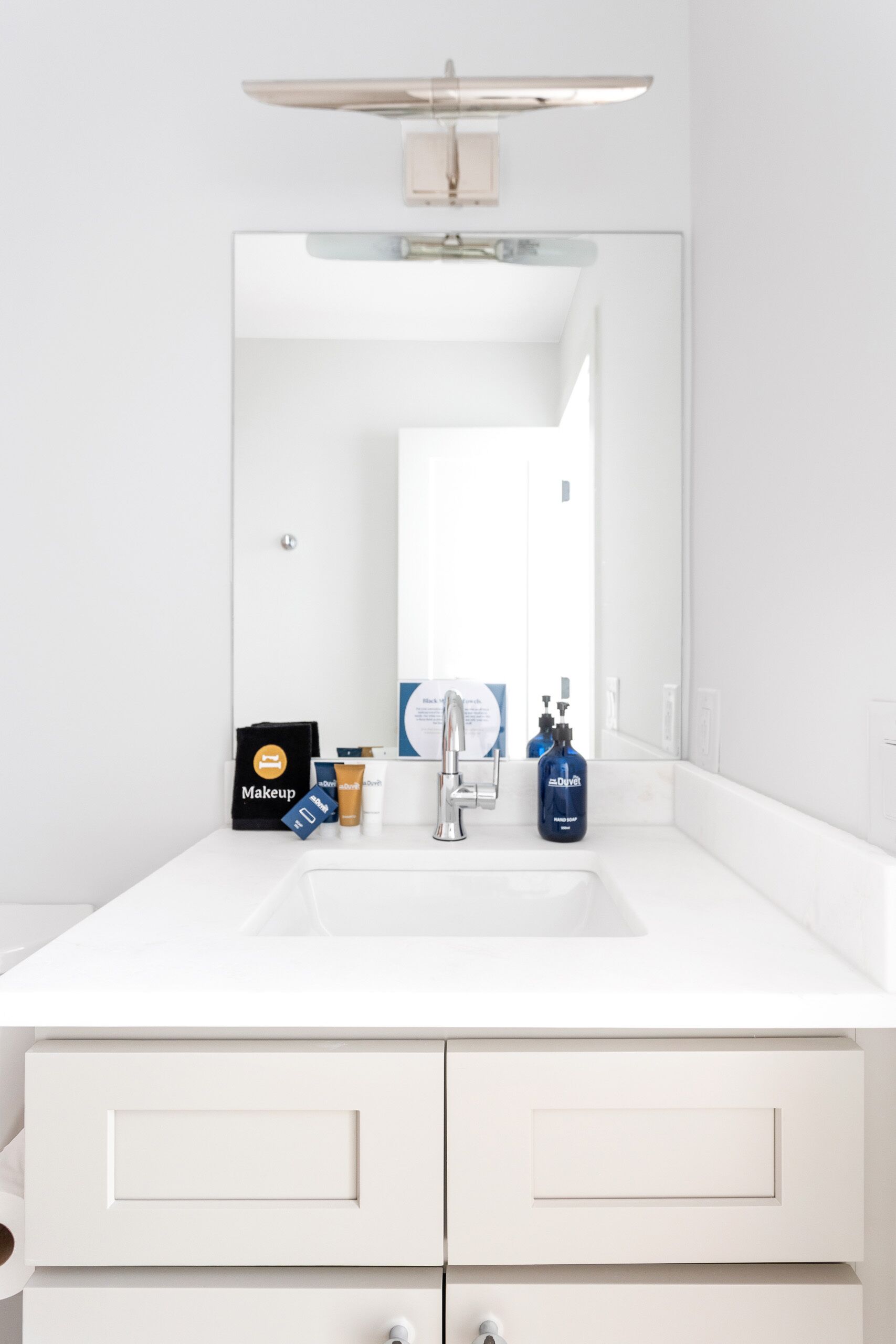 Un baño moderno con un tocador blanco, un espejo grande y un lavamanos.