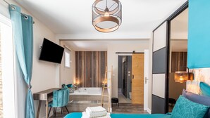 A modern bedroom with a bed, a desk, a chair, a TV, a bathtub, and a wooden wall. - Villa La Roche Rouge (Pougnadoresse)