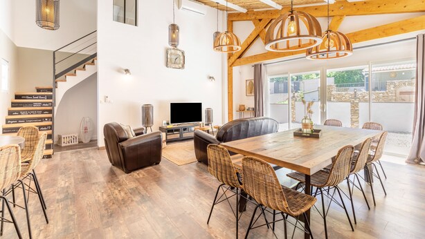 A spacious living area with a wooden dining table, wicker chairs, a leather sofa, and a TV. - Villa La Roche Rouge (Pougnadoresse)