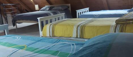 A dormitory-style room with two beds, a bunk bed, and a skylight.