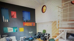 A modern interior with a glass table, seating area, and a wall displaying various artworks.
