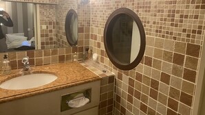 A bathroom with a sink, mirror, and tiled walls.