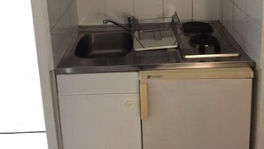 A compact kitchen with a sink, stove, and storage cabinets. - Logement Clair ET Spacieux (Paris)