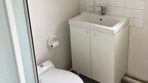 A small, white bathroom with a toilet, a sink, and a mirror above the sink. - Logement Clair ET Spacieux (Paris)