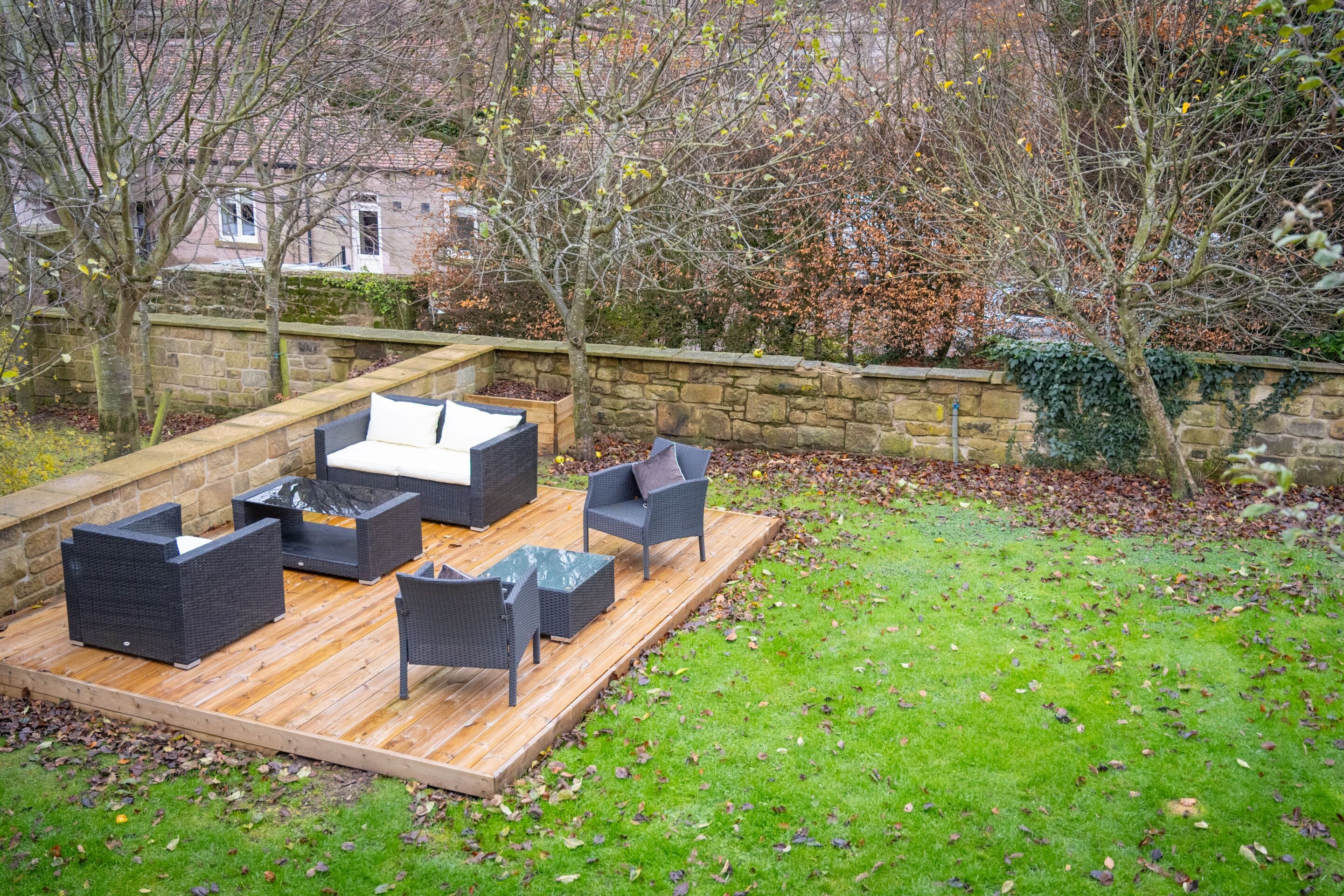Une terrasse extérieure avec des meubles en osier et une plateforme en bois.