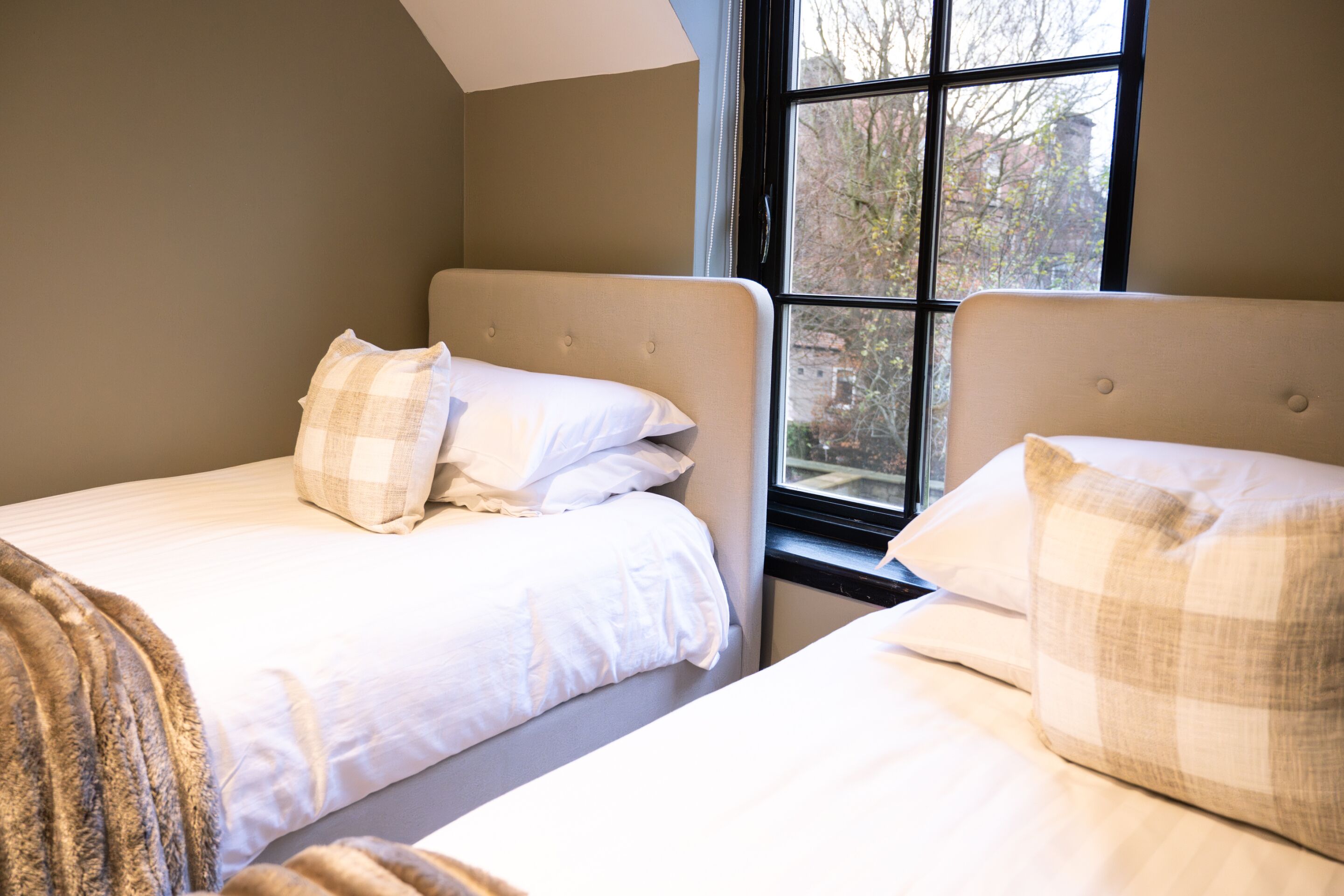 A bedroom with two beds, each with a headboard and pillows.
