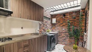 A compact kitchen with wooden cabinets, a built-in stove, and a washing machine. - Cozy corner in El Poblado! (Medellín)