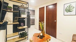 A modern living room with a wooden coffee table, a black metal shelf unit with plants, and a framed artwork on the wall. - Cozy corner in El Poblado! (Medellín)