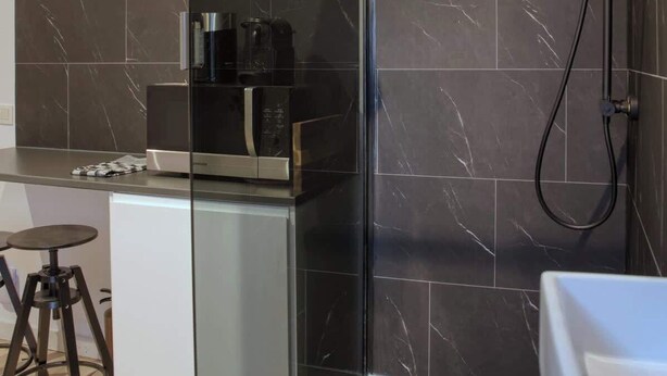 Une salle de bain moderne dotée d’une douche à parois de verre, d’un espace café intégré et d’un petit coin salon.