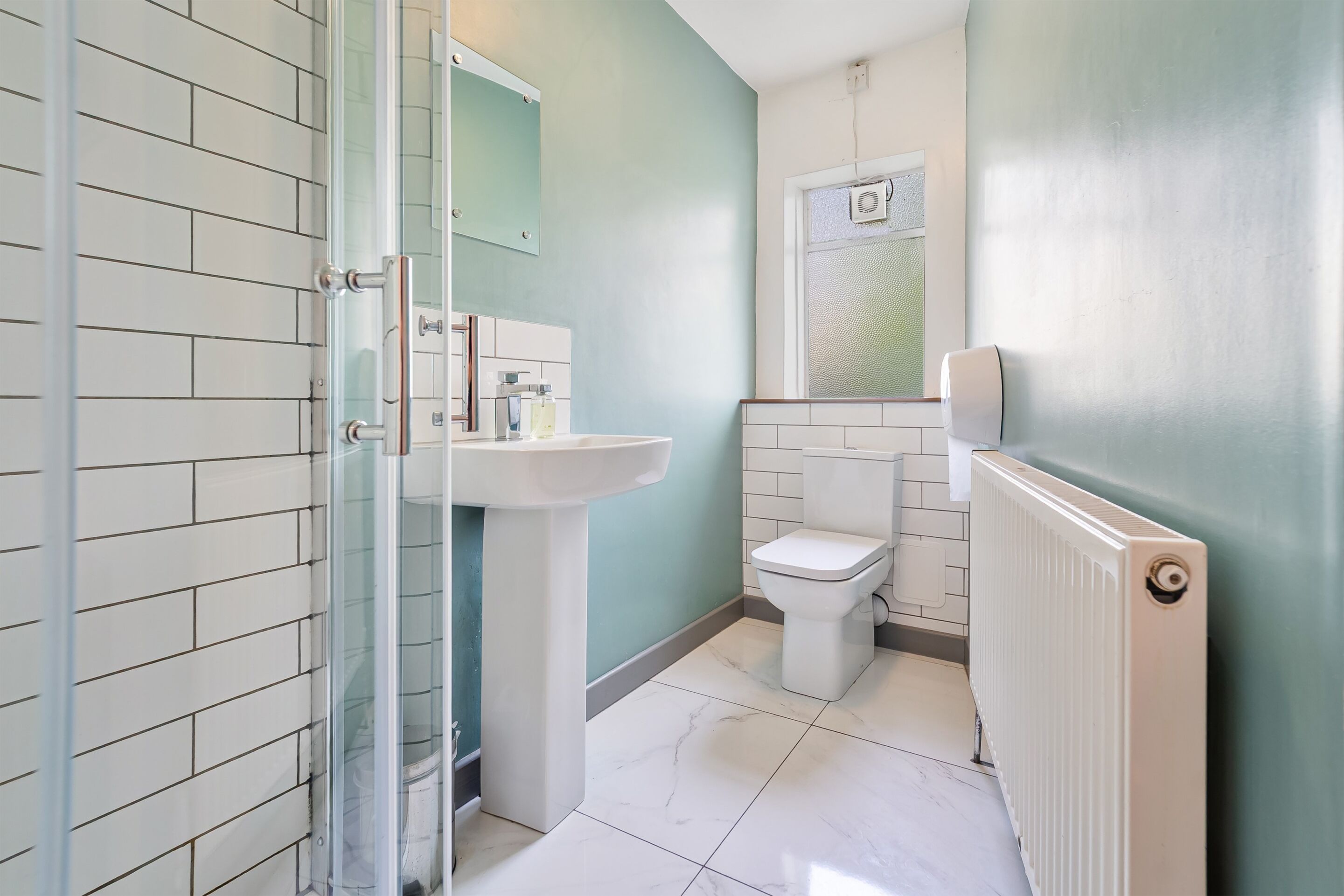Un baño con cabina de ducha de vidrio, un lavamanos blanco y un inodoro.