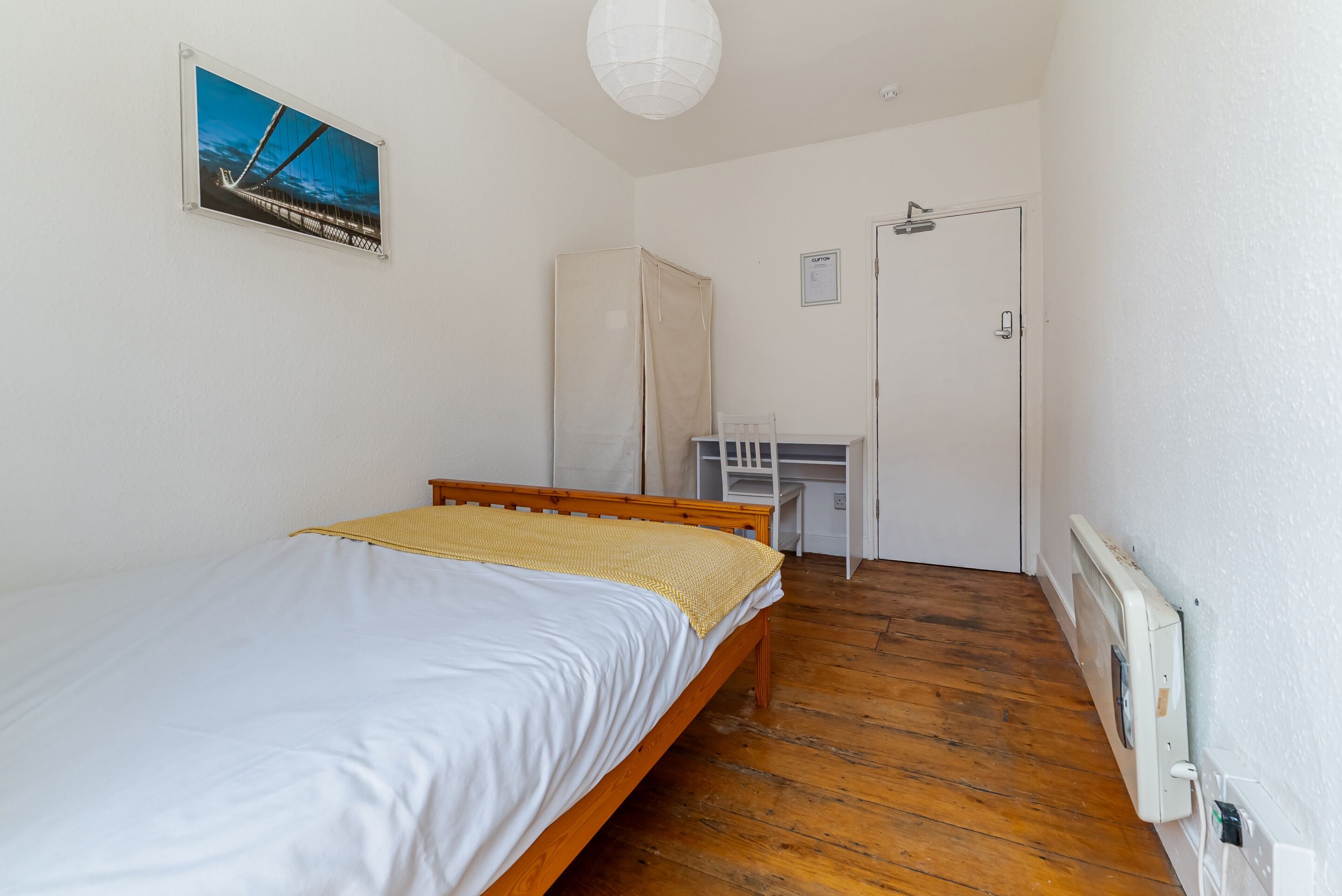 Un dormitorio con una cama de madera, un escritorio y un radiador.