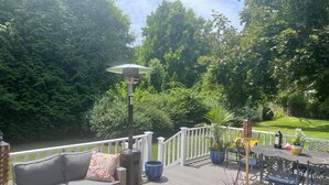 Eine Terrasse mit einer Couch, Stühlen und einem Tisch, umgeben von Topfpflanzen und einem Geländer.