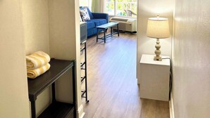 A hotel room with a bed, a desk, a chair, a sofa, and a window with a view of the outdoors. - Waters Edge  - Ocean View at Symphony Beach Club! (Ormond Beach)