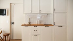 Una cocina con armarios blancos, una encimera de madera y un microondas integrado.