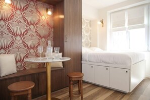 A room with a bed, a round table with stools, and a patterned wall. - Charmant Appartement à Montmartre - 4P - Paris 18 (Paris)