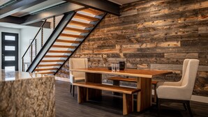 A modern interior with a wooden staircase, a dining area with a wooden table and chairs, and a rustic wall. - Eagles View- Perfect location near downtown Cody, New Luxury Family Condo (Cody)