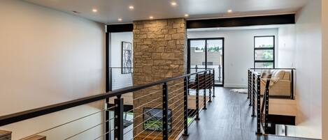 A modern interior with a stone accent wall, a staircase with metal railings, and a seating area with a sofa and a coffee table.