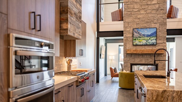 A modern kitchen with wooden cabinets, a built-in oven, and a stone accent wall. - Eagles View- Perfect location near downtown Cody, New Luxury Family Condo (Cody)
