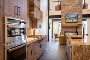 Une cuisine moderne avec des meubles en bois, un four encastré et un mur d’accent en pierre.
