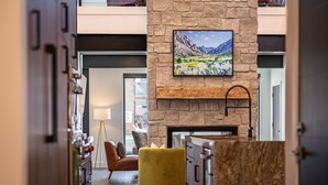 A modern lobby with a stone fireplace, a yellow ottoman, and a painting of a mountain landscape. - Eagles View- Perfect location near downtown Cody, New Luxury Family Condo (Cody)