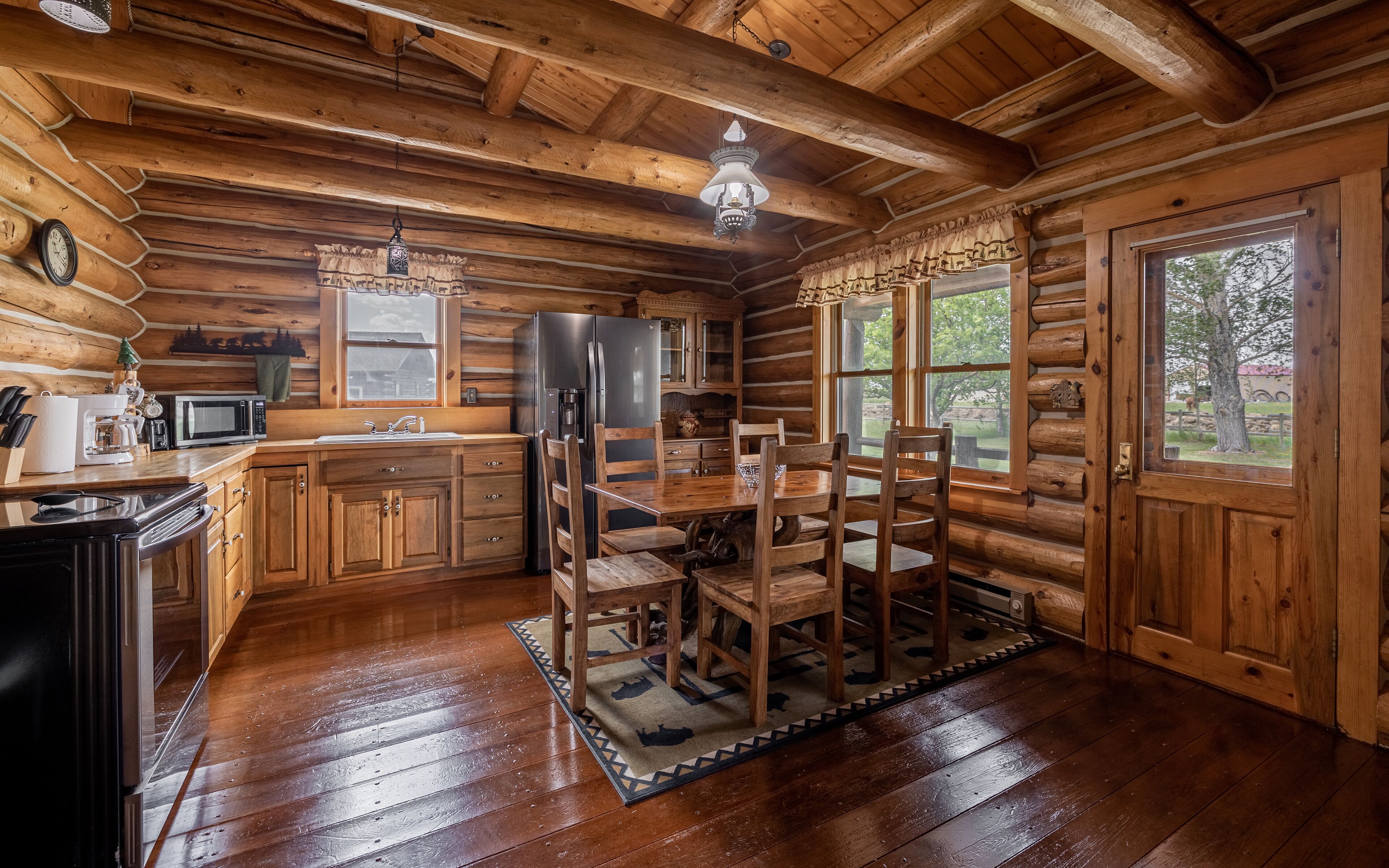 L’intérieur d’une cabane en rondins, avec une table à manger en bois, des chaises, un réfrigérateur, un four à micro-ondes et un évier.