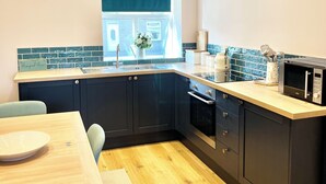 A modern kitchen with dark cabinets, a wooden countertop, and a built-in oven. - Inviting Townhouse in Bedlington (Bedlington)