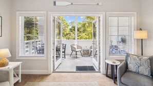 Una habitación con puerta de vidrio corrediza que da a un espacio exterior con mobiliario de patio.