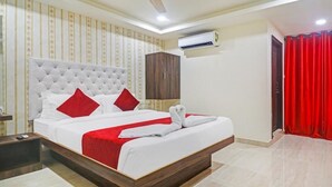 A hotel room with a large bed, a wooden headboard, a wardrobe, an air conditioning unit, and a red curtain. - HOTEL BRIGHT AIRPORT ZONE SHAMSHABAD (Hyderabad)