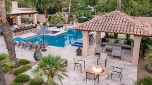 Una zona de piscina con un pozo de fuego y mobiliario exterior.