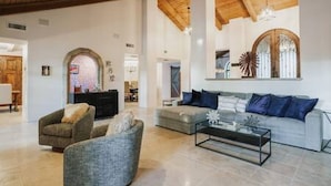 Un amplio salón con techo alto, chimenea y un ventanal grande.