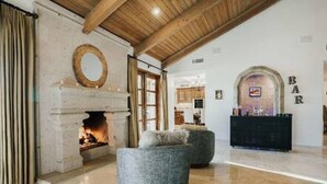 Amplia sala de estar con chimenea, dos sillones grises y techo de madera.