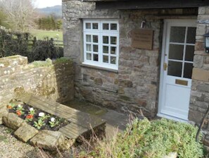 Situated in a natural setting, this charming building features a traditional design with a white door and window.