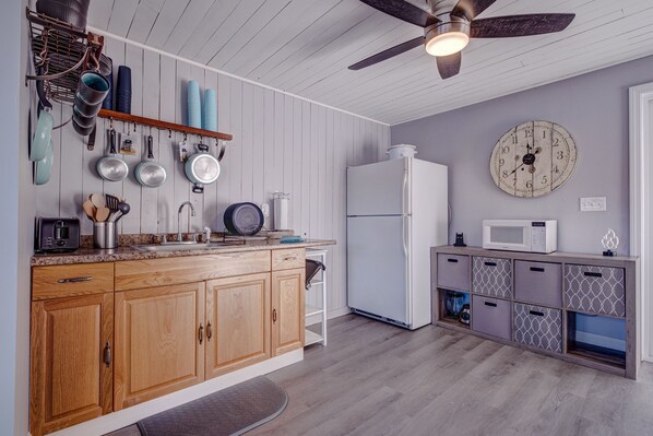 A kitchen with wooden cabinets, a white refrigerator, and a clock on the wall.