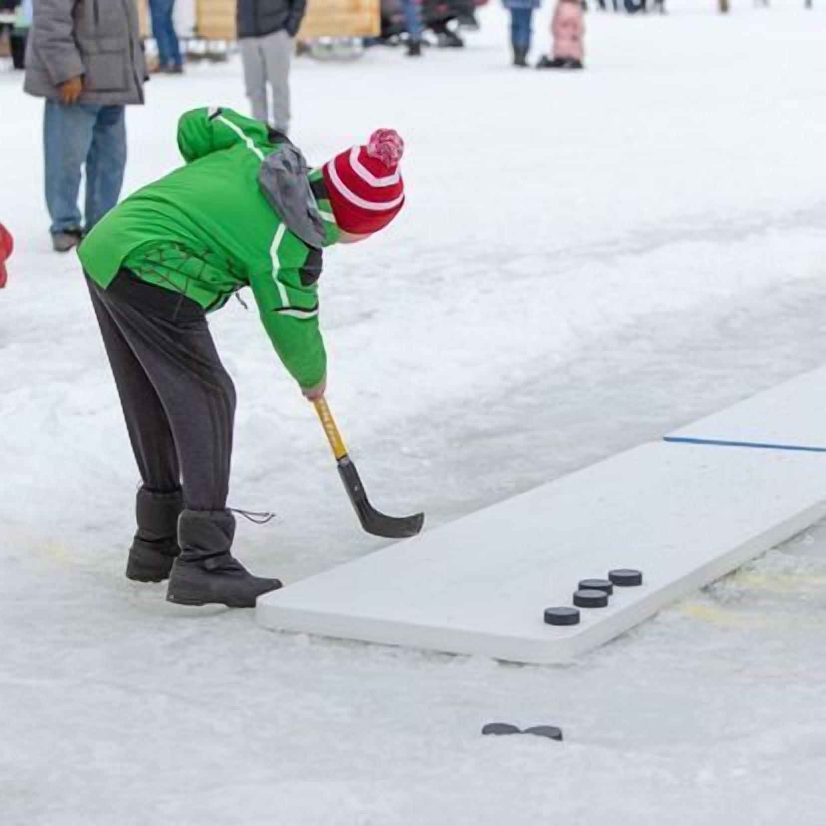 A person playing hockey on a frozen surface with a puck and a stick.