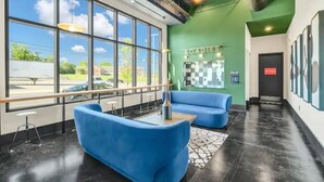 A modern lobby with large windows, blue seating, and a green accent wall.