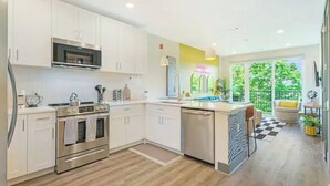 A modern kitchen with white cabinets, stainless steel appliances, and a large island.