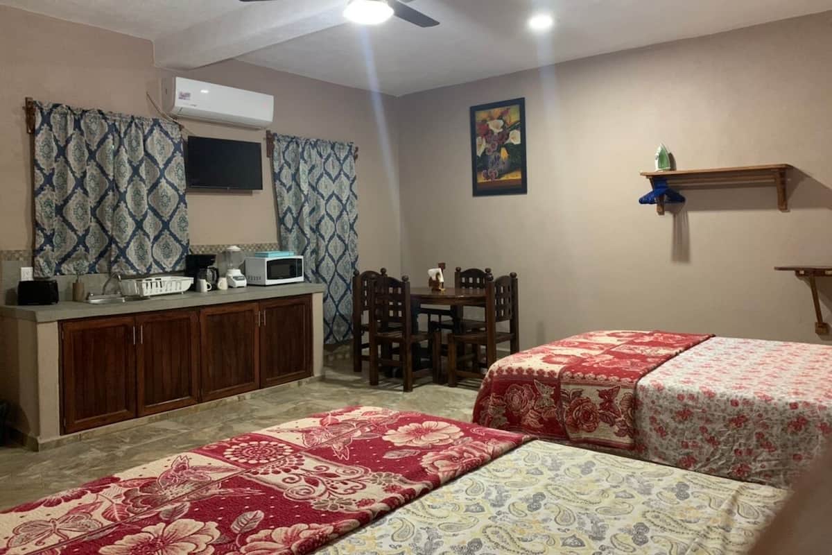 A bedroom with two beds, a desk with a computer, a chair, and a ceiling fan.