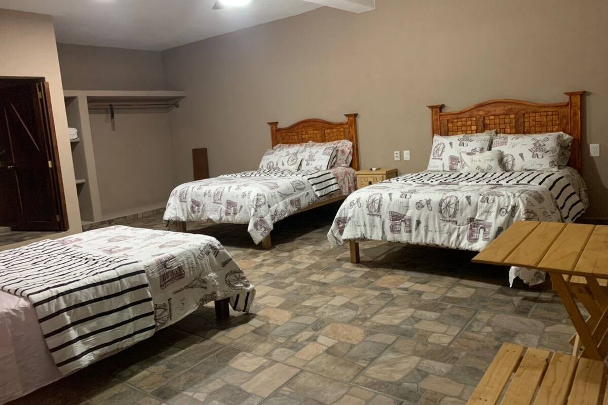 A bedroom with two single beds, a wooden table, and a wardrobe.
