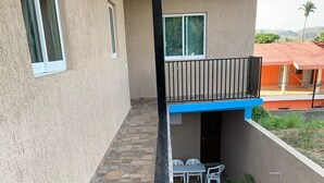A building with a stone-tiled patio, a red hexagonal tile area, and a small white table with chairs. - Bungalows Victoria (La Manzanilla)