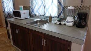 A kitchen with a microwave, sink, blender, and coffee maker on the counter. - Bungalows Victoria (La Manzanilla)