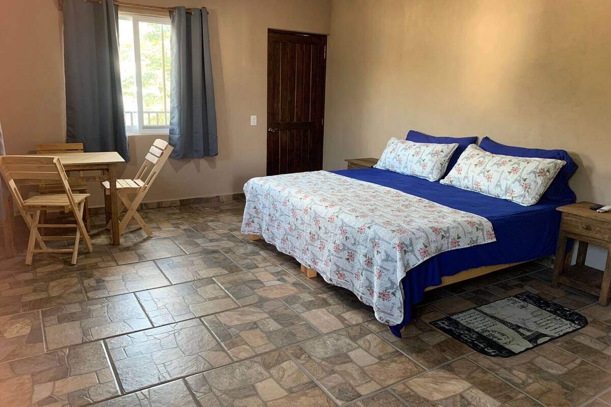 A bedroom with a bed, a desk, and chairs.