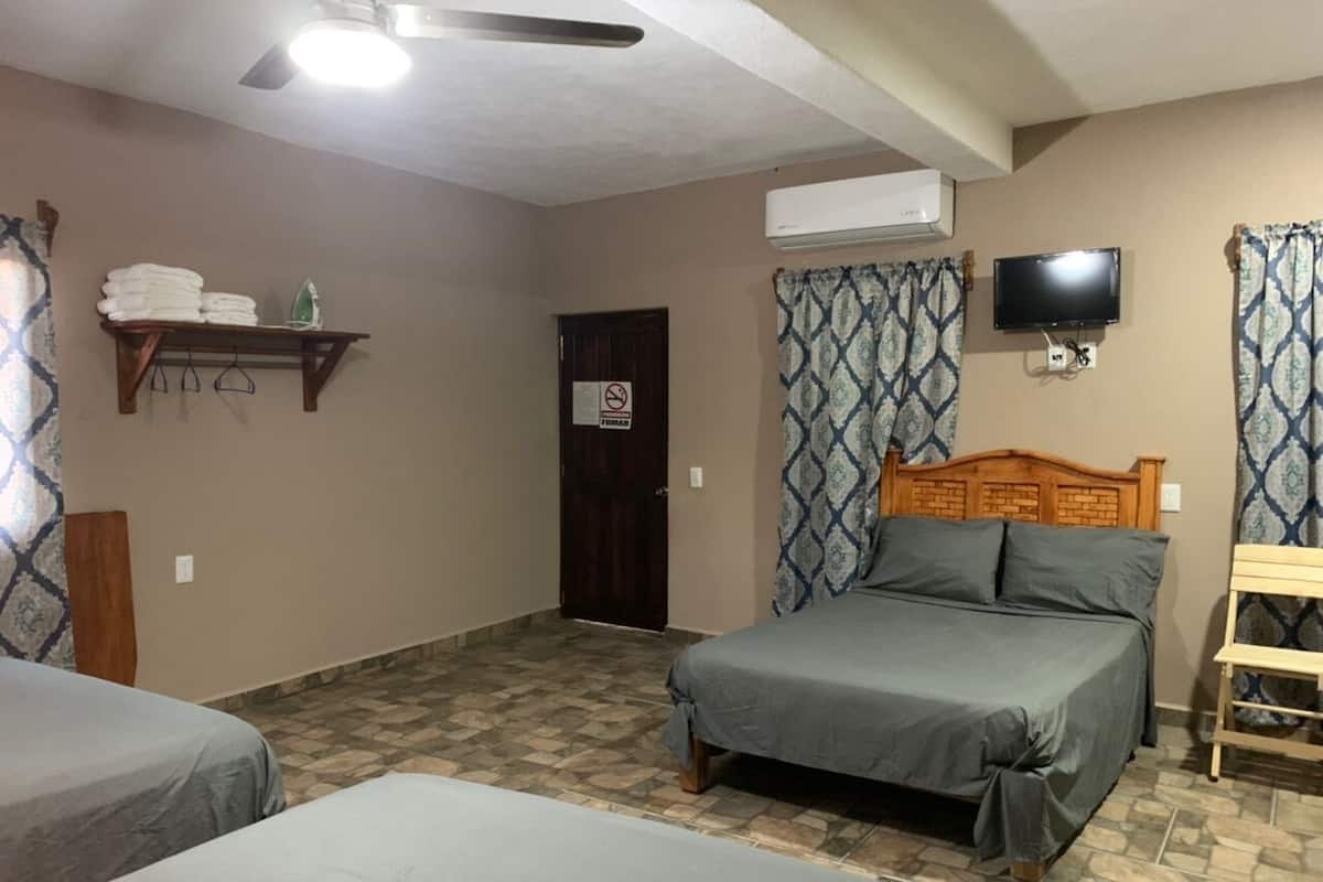 A room with two beds, a wooden headboard, a television, and an air conditioning unit.