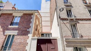 A multi-story building with a prominent brown door, brick and stucco facades, and small balconies. - Cute & Bright Studio in a Courtyard-Montmartre(5) (Paris)