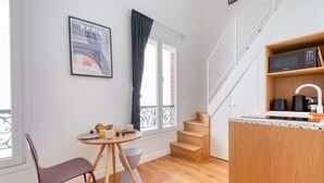 A compact kitchen with a dining area, a staircase, and a view of the Eiffel Tower. - Cute & Bright Studio in a Courtyard-Montmartre(5) (Paris)